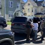 Three armed and masked United States Immigrations and Customs Enforcement (ICE) agents detaining man on Bates Place in Danbury. Folded papers can be seen in the man’s cuffed hands.